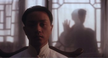 Movie still from “Farewell My Concubine” (1992), directed by Kaige Chen – A man in a white shirt is looking at the camera; Close Up shot, Over the shoulder angle