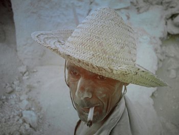 An old man wearing a straw hat smoking a cigarette