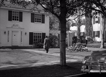Movie still from “Father of the Bride” (1950), directed by Vincente Minnelli – A person walking in front of a house near a tree; Extreme Wide shot, High angle