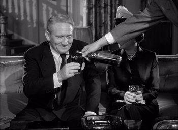 Movie still from “Father of the Bride” (1950), directed by Vincente Minnelli – An older man sitting in front of a bottle of wine; Medium shot, Low angle