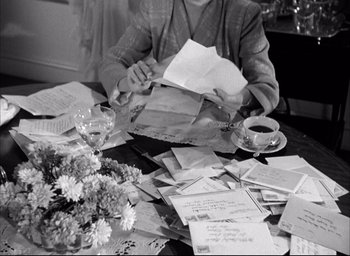 Movie still from “Father of the Bride” (1950), directed by Vincente Minnelli – A person sitting at a table writing on a piece of paper; Medium shot, High angle