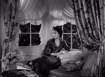 Movie still from “Father of the Bride” (1950), directed by Vincente Minnelli – A woman sitting on top of a couch in a room; Medium shot, High angle