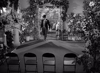 Movie still from “Father of the Bride” (1950), directed by Vincente Minnelli – A black and white photo of a man in a suit and top hat walking down the aisle; Wide shot, High angle