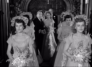 Movie still from “Father of the Bride” (1950), directed by Vincente Minnelli – A group of women in wedding dresses standing in front of a man in a suit; Medium shot, Low angle