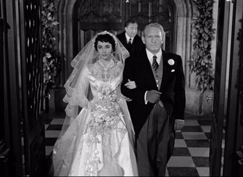 Movie still from “Father of the Bride” (1950), directed by Vincente Minnelli – An old photo of a man and a woman walking down the aisle; Medium shot, High angle