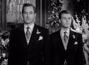 Movie still from “Father of the Bride” (1950), directed by Vincente Minnelli – Two men in suits standing next to each other in front of a christmas tree; Medium shot, Low angle