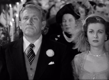 Movie still from “Father of the Bride” (1950), directed by Vincente Minnelli – An older man and a younger woman standing next to each other in front of an older woman; Medium shot, Low angle