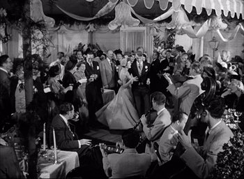 Movie still from “Father of the Bride” (1950), directed by Vincente Minnelli – A group of people sitting in a room; Wide shot, High angle