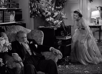 Movie still from “Father of the Bride” (1950), directed by Vincente Minnelli – An older man sitting in a chair in front of a woman; Wide shot, High angle