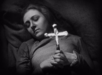 Movie still from “Faust” (1926), directed by F.W. Murnau – A woman holding a cross in her hands; Close Up shot, High angle