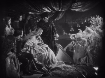 Movie still from “Faust” (1926), directed by F.W. Murnau – A group of people gathered around a man in a black suit; Wide shot, High angle