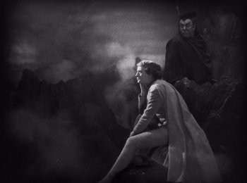 Movie still from “Faust” (1926), directed by F.W. Murnau – A woman sitting on the ground next to a demon; Wide shot, High angle