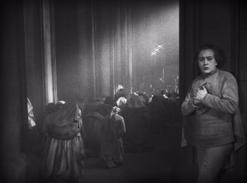 Movie still from “Faust” (1926), directed by F.W. Murnau – A black and white photo of people sitting in a room; Wide shot, High angle