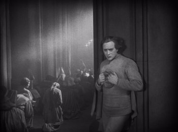 Movie still from “Faust” (1926), directed by F.W. Murnau – A man standing next to a crowd of people in a room; Wide shot, High angle