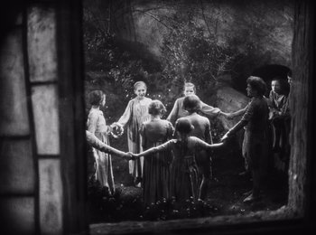 Movie still from “Faust” (1926), directed by F.W. Murnau – A black and white photo of a group of people holding hands in a circle; Wide shot, High angle