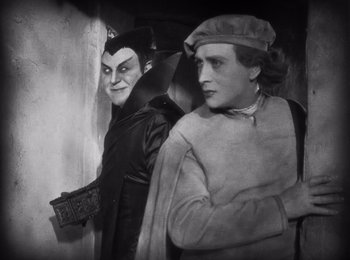 Movie still from “Faust” (1926), directed by F.W. Murnau – A man and a woman dressed up in costumes; Medium shot, Over the shoulder angle