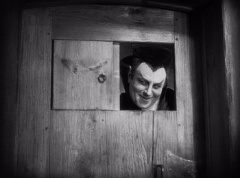 Movie still from “Faust” (1926), directed by F.W. Murnau – A man with a hat looking through a window; Medium shot, Low angle