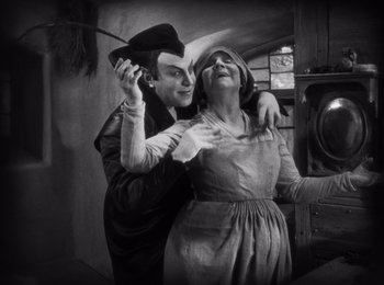 Movie still from “Faust” (1926), directed by F.W. Murnau – An old photo of a man and a woman posing for a picture; Medium shot, High angle