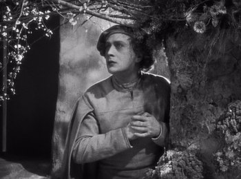 Movie still from “Faust” (1926), directed by F.W. Murnau – A man standing next to a tree with his hand on his chest; Medium shot, Low angle