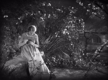 Movie still from “Faust” (1926), directed by F.W. Murnau – A woman in a long white dress standing next to a bush; Wide shot, High angle