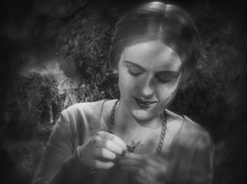 Movie still from “Faust” (1926), directed by F.W. Murnau – A young woman holding a plant in her hands; Close Up shot, High angle
