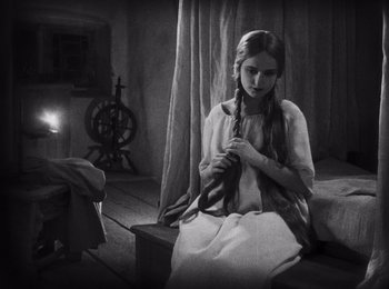 Movie still from “Faust” (1926), directed by F.W. Murnau – A young girl sitting on the floor holding a pair of braids; Medium shot, High angle