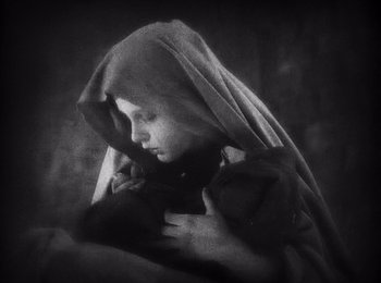 Movie still from “Faust” (1926), directed by F.W. Murnau – A young child wrapped in a blanket looking sad; Close Up shot, High angle