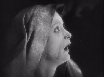 Movie still from “Faust” (1926), directed by F.W. Murnau – A black - and - white photo of a woman with a hood over her head; Close Up shot, Low angle