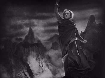 Movie still from “Faust” (1926), directed by F.W. Murnau – An old photo of a man holding a spear in a mountainous area; Wide shot, Low angle