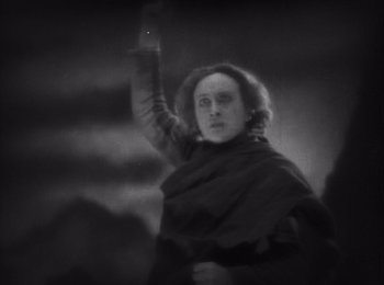Movie still from “Faust” (1926), directed by F.W. Murnau – A black and white photo of a man holding a sword; Medium shot, Low angle