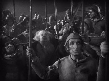 Movie still from “Faust” (1926), directed by F.W. Murnau – A group of men in medieval garb holding wooden poles; Medium shot, High angle