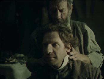 Movie still from “Faust” (2011), directed by Aleksandr Sokurov – A man is getting his hair combed by another man; Close Up shot, Over the shoulder angle