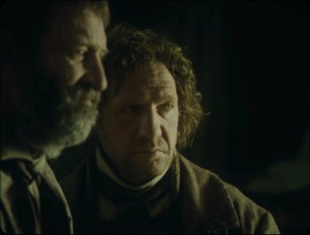 Movie still from “Faust” (2011), directed by Aleksandr Sokurov – A man with a beard is looking at a man with curly hair; Close Up shot, Over the shoulder angle