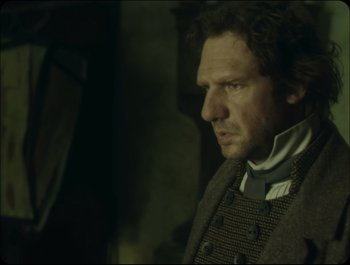 Movie still from “Faust” (2011), directed by Aleksandr Sokurov – A person wearing a suit and tie; Close Up shot, Over the shoulder angle