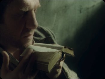 Movie still from “Faust” (2011), directed by Aleksandr Sokurov – A person holding an open book; Close Up shot, Over the shoulder angle