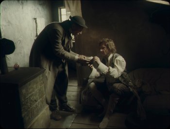 Movie still from “Faust” (2011), directed by Aleksandr Sokurov – Two men are sitting in a room and one of them is holding something in his hand; Wide shot, High angle