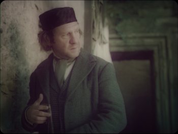 Movie still from “Faust” (2011), directed by Aleksandr Sokurov – A man wearing a hat and a coat; Medium shot, Low angle