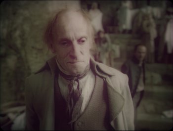 Movie still from “Faust” (2011), directed by Aleksandr Sokurov – An old man in a suit and a tie; Medium shot, High angle