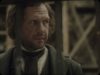 Movie still from “Faust” (2011), directed by Aleksandr Sokurov – A person wearing a suit and tie; Close Up shot, Over the shoulder angle