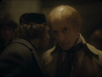 Movie still from “Faust” (2011), directed by Aleksandr Sokurov – Two men in a dark room , one of whom is wearing a tie; Close Up shot, Over the shoulder angle