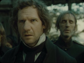 Movie still from “Faust” (2011), directed by Aleksandr Sokurov – A man with a beard is standing next to another man with a beard; Close Up shot, Over the shoulder angle