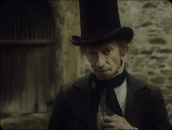 Movie still from “Faust” (2011), directed by Aleksandr Sokurov – An old man wearing a top hat and a tie; Close Up shot, Over the shoulder angle
