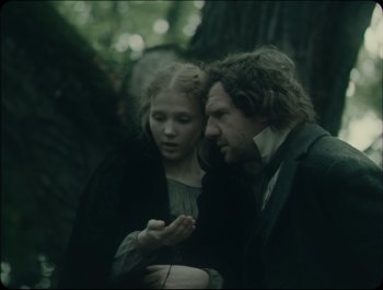 Movie still from “Faust” (2011), directed by Aleksandr Sokurov – A man and a woman standing next to each other in a forest; Medium shot, Over the shoulder angle