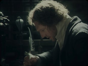 Movie still from “Faust” (2011), directed by Aleksandr Sokurov – A man with long curly hair is holding a feather; Close Up shot, Over the shoulder angle