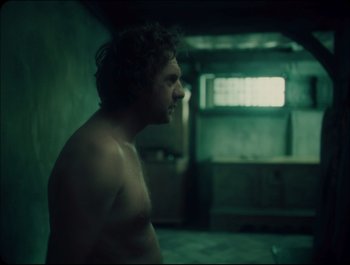 Movie still from “Faust” (2011), directed by Aleksandr Sokurov – A man standing in a room with a window in the background; Medium shot, Over the shoulder angle