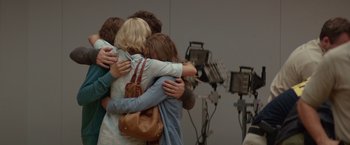 Movie still from “The Shack” (2017), directed by Stuart Hazeldine – A group of people hugging in front of some lights; Medium shot, Over the shoulder angle