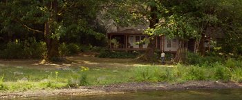 Movie still from “The Shack” (2017), directed by Stuart Hazeldine – A person standing in front of a house in the woods; Extreme Wide shot, High angle
