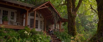 Movie still from “The Shack” (2017), directed by Stuart Hazeldine – A woman sitting on the steps of a wooden house; Wide shot, Low angle