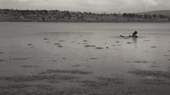 Movie still from “Faya Dayi” (2021), directed by Jessica Beshir – A black and white photo of a body of water; Extreme Wide shot, High angle