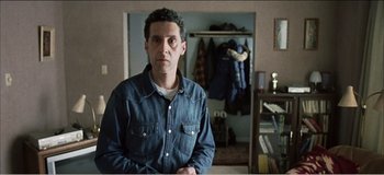 Movie still from “Fear X” (2003), directed by Nicolas Winding Refn – A man standing in front of an open closet; Medium shot, Over the shoulder angle